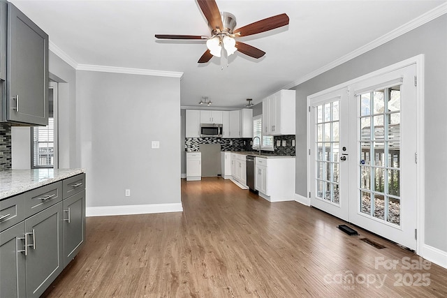 kitchen with appliances with stainless steel finishes, white cabinets, tasteful backsplash, and gray cabinets