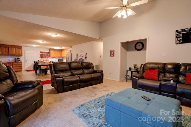 living area featuring baseboards, a ceiling fan, light colored carpet, vaulted ceiling, and a textured ceiling