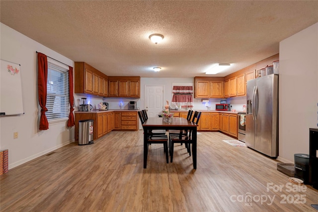 kitchen with brown cabinets, light wood-style floors, stainless steel appliances, and light countertops