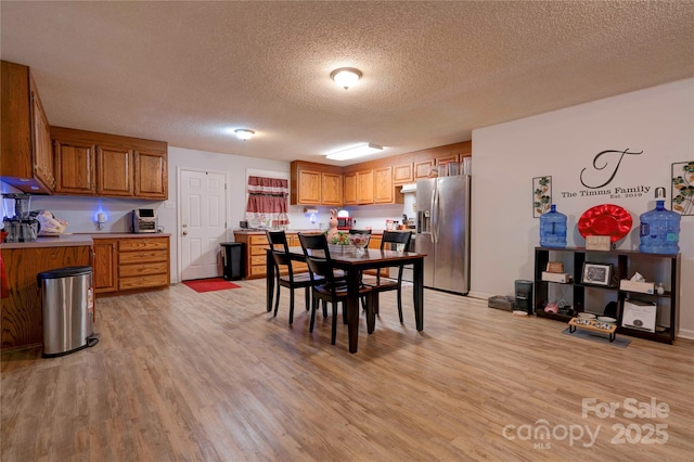 dining room featuring light wood-type flooring and a textured ceiling