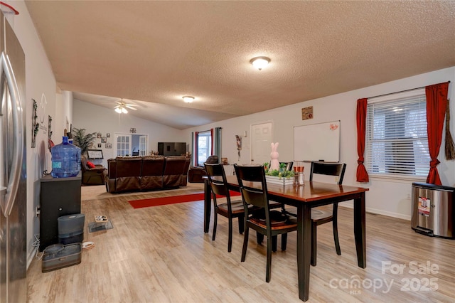 dining space with lofted ceiling, ceiling fan, light wood finished floors, and a textured ceiling