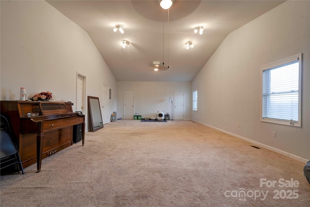 interior space with carpet floors, visible vents, high vaulted ceiling, and baseboards