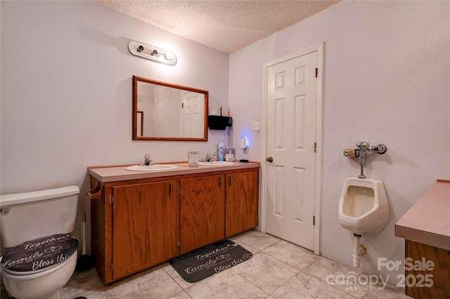 bathroom with a sink, a textured ceiling, toilet, and double vanity