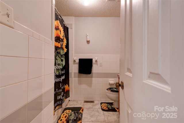 full bathroom featuring toilet, tile walls, a textured ceiling, and a shower with shower curtain