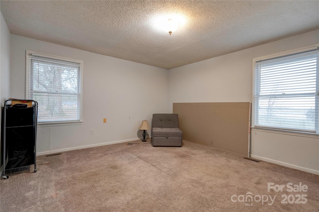 unfurnished room featuring carpet floors, baseboards, visible vents, and a textured ceiling