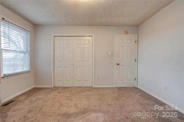 unfurnished bedroom with carpet floors, a closet, visible vents, and baseboards