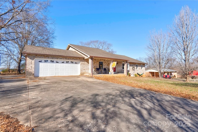 ranch-style home with a garage, concrete driveway, covered porch, a front lawn, and brick siding