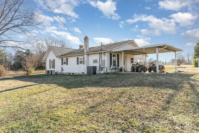 rear view of house featuring cooling unit and a yard