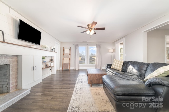 living room featuring a fireplace, built in features, ceiling fan, and dark wood-type flooring