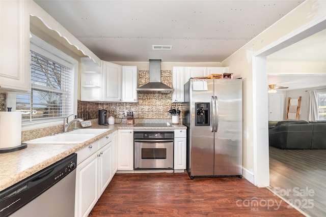 kitchen with white cabinets, wall chimney exhaust hood, stainless steel appliances, sink, and backsplash