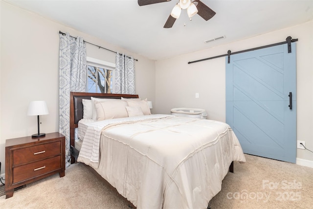 carpeted bedroom with ceiling fan and a barn door