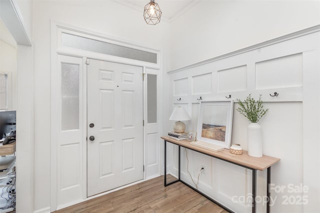 foyer with ornamental molding and light hardwood / wood-style flooring