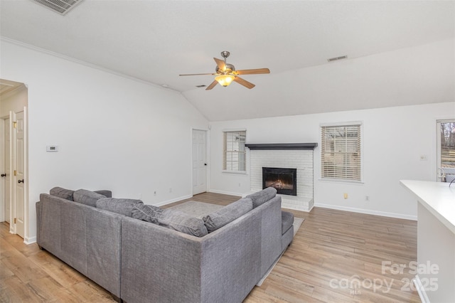 living room featuring lofted ceiling, a fireplace, light wood-type flooring, and ceiling fan