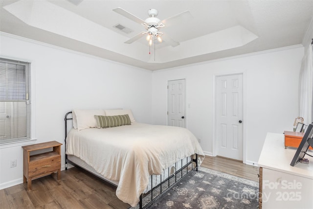 bedroom featuring a raised ceiling, ceiling fan, crown molding, and dark wood-type flooring