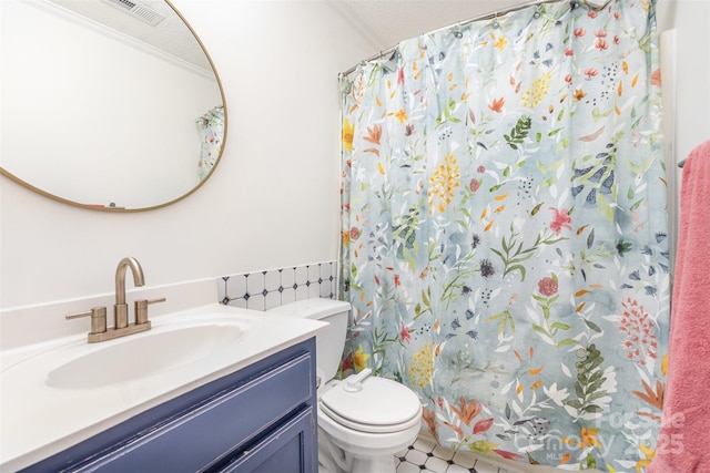 bathroom featuring a textured ceiling, ornamental molding, toilet, walk in shower, and vanity