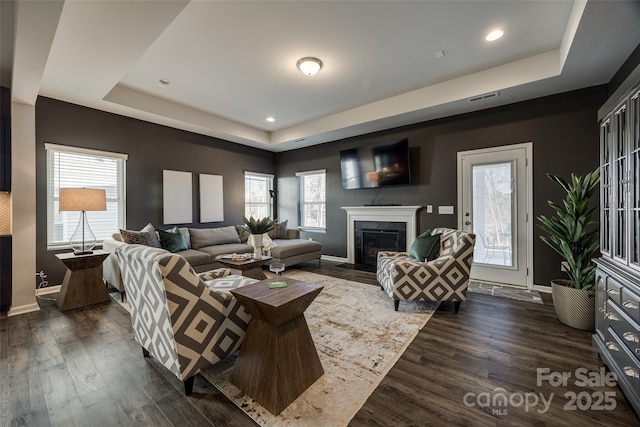 living room featuring dark hardwood / wood-style flooring and a tray ceiling