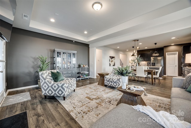 living room featuring a tray ceiling and dark hardwood / wood-style floors