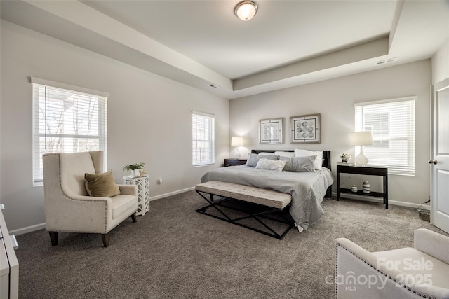 carpeted bedroom featuring multiple windows and a tray ceiling