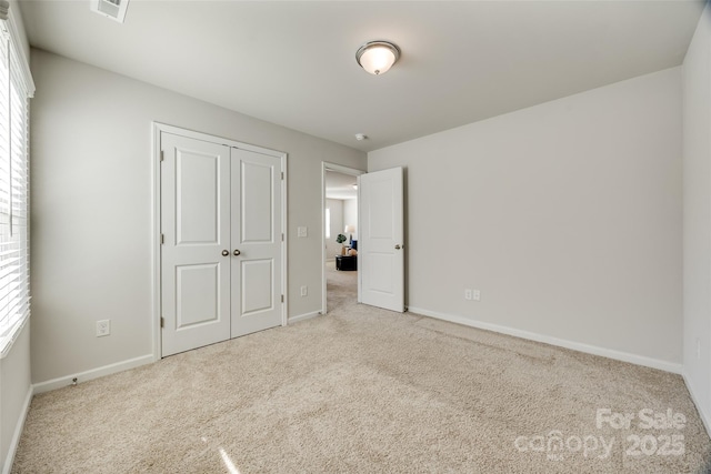 unfurnished bedroom featuring a closet and light colored carpet