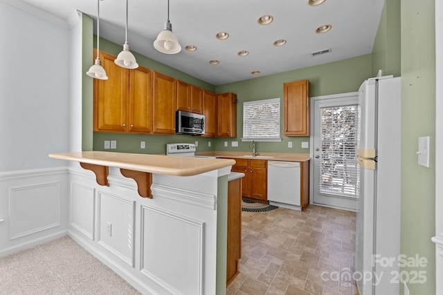 kitchen featuring a breakfast bar, sink, decorative light fixtures, kitchen peninsula, and white appliances