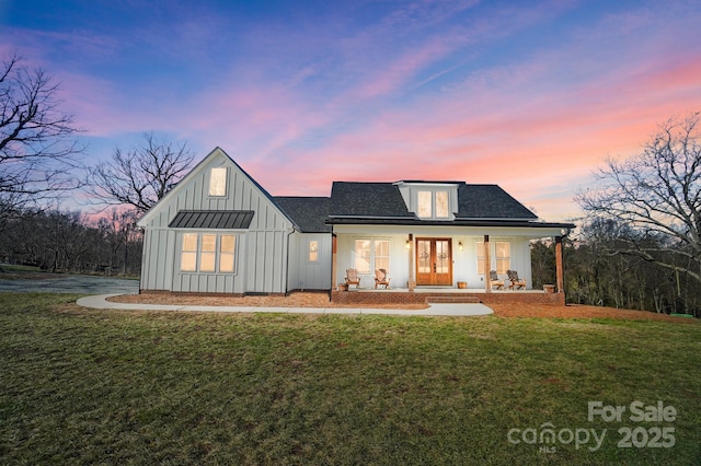 back house at dusk featuring a porch, a yard, and french doors