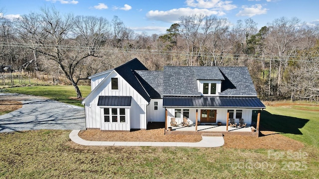 rear view of house with a porch and a lawn