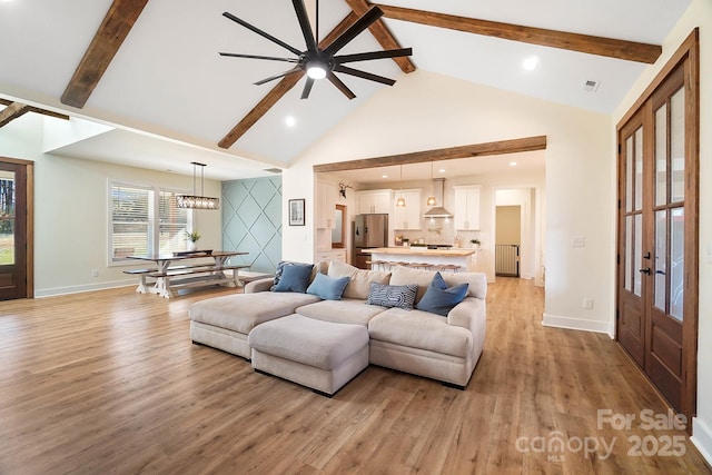 living room with vaulted ceiling with beams, ceiling fan, and light hardwood / wood-style floors