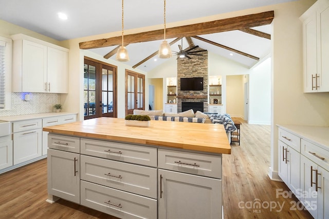 kitchen with decorative backsplash, french doors, a fireplace, white cabinets, and butcher block countertops