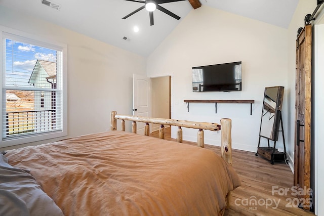 bedroom featuring ceiling fan, a barn door, beamed ceiling, high vaulted ceiling, and wood-type flooring