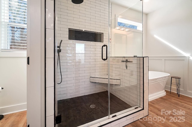 bathroom with plenty of natural light, independent shower and bath, and hardwood / wood-style flooring