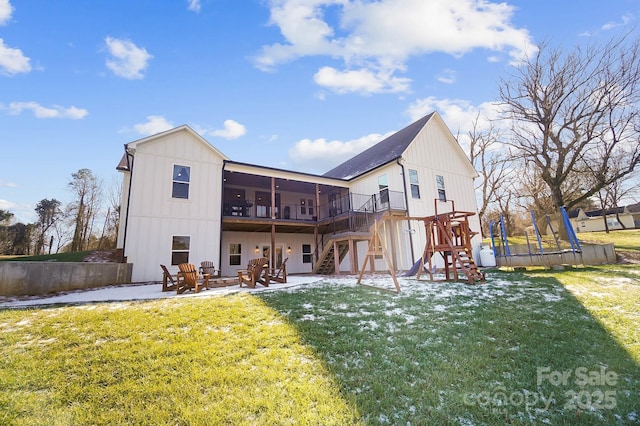 rear view of property featuring a lawn, a sunroom, a patio, and a trampoline