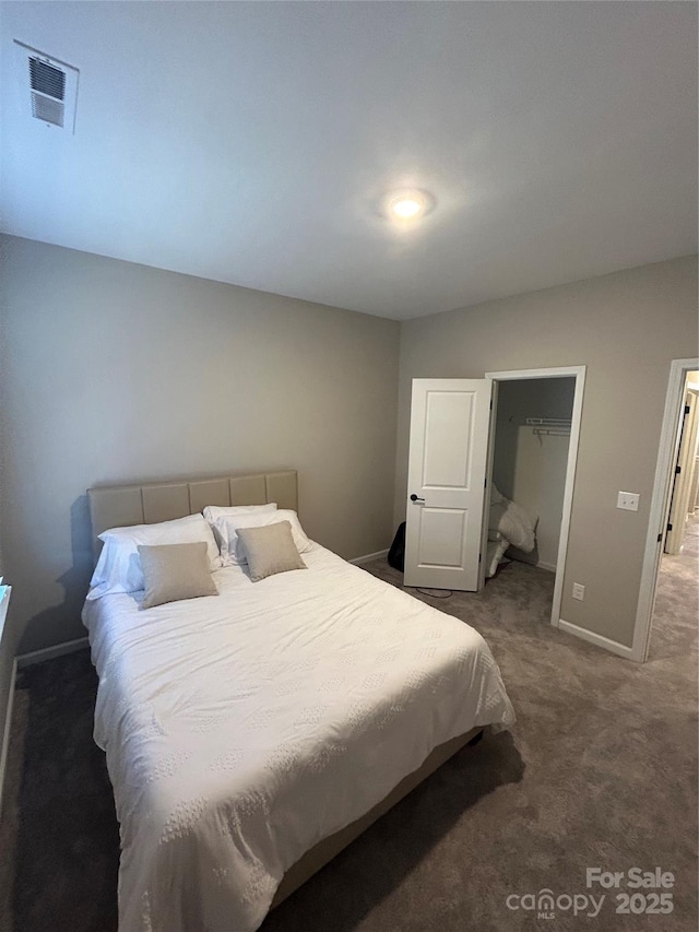 bedroom featuring a spacious closet, dark colored carpet, and a closet