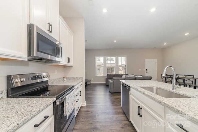 kitchen featuring sink, light stone counters, appliances with stainless steel finishes, dark hardwood / wood-style floors, and white cabinets