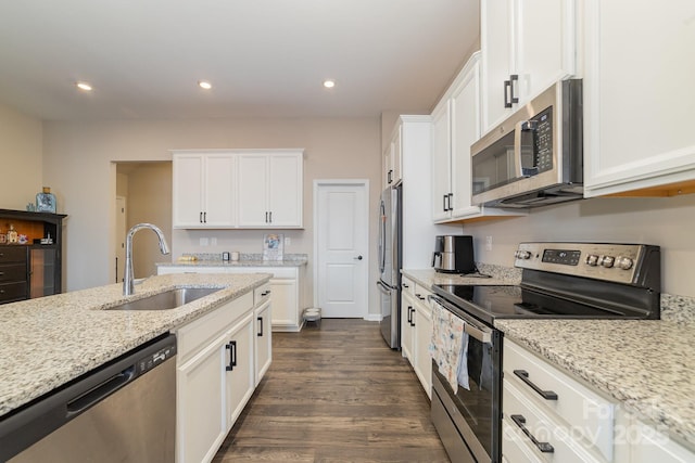 kitchen with sink, white cabinetry, stainless steel appliances, dark hardwood / wood-style floors, and light stone counters