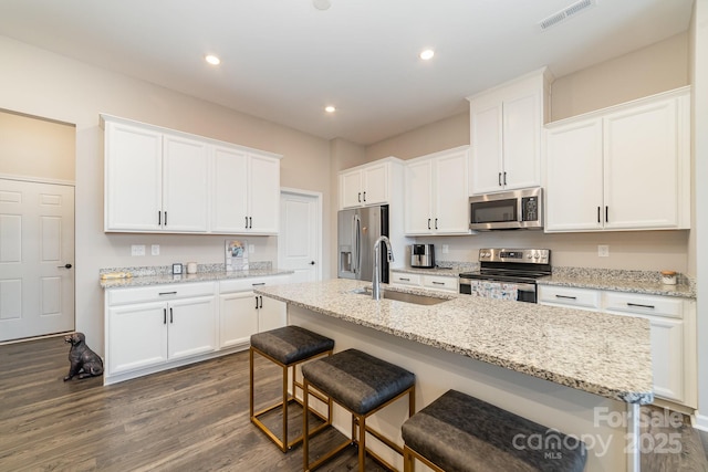 kitchen with white cabinetry, appliances with stainless steel finishes, a kitchen island with sink, and sink