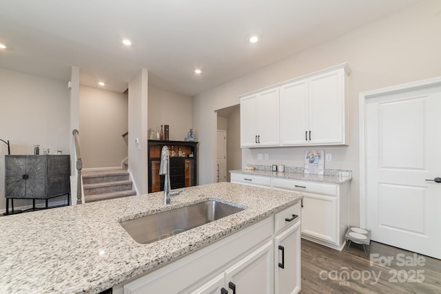 kitchen with white cabinetry, sink, dark wood-type flooring, and light stone countertops