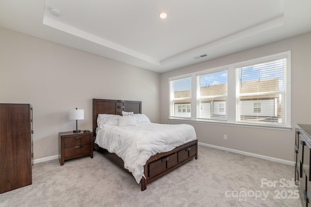 bedroom with light carpet and a tray ceiling