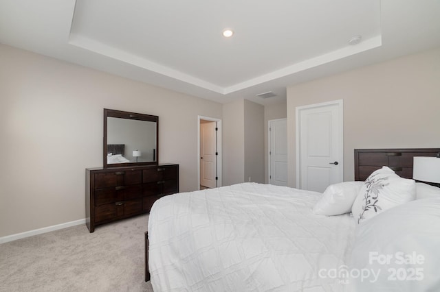 bedroom featuring light colored carpet and a tray ceiling