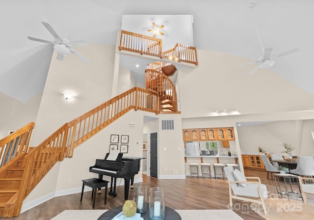 living area with stairway, visible vents, wood finished floors, and ceiling fan