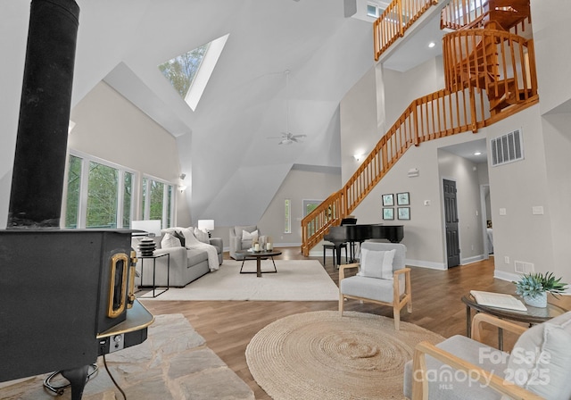 living area with baseboards, stairs, visible vents, a skylight, and wood finished floors