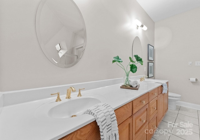 bathroom featuring tile patterned flooring, double vanity, a sink, and toilet