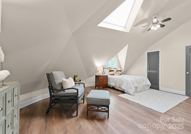 bedroom featuring lofted ceiling with skylight, baseboards, a ceiling fan, and wood finished floors