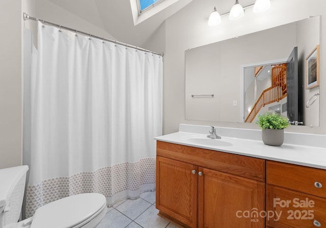 bathroom with vaulted ceiling with skylight, vanity, tile patterned flooring, toilet, and curtained shower