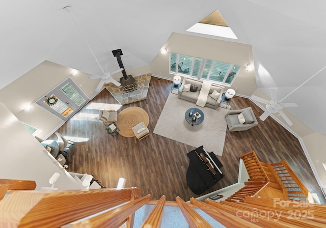 living room with high vaulted ceiling, ceiling fan, wood finished floors, and a wood stove