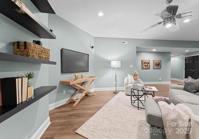living area featuring visible vents, baseboards, a ceiling fan, and wood finished floors