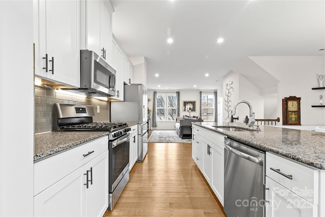 kitchen featuring appliances with stainless steel finishes, sink, dark stone counters, and white cabinets