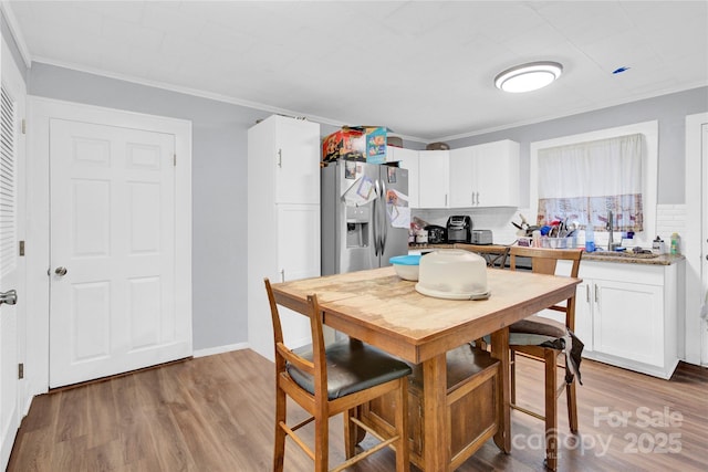 kitchen with white cabinetry, light hardwood / wood-style flooring, stainless steel refrigerator with ice dispenser, and ornamental molding