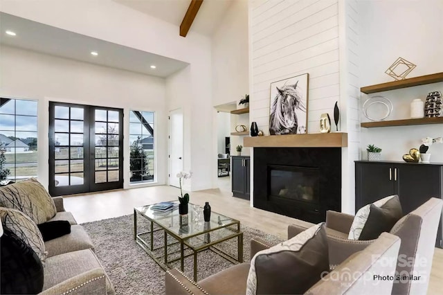 living room with a large fireplace, a towering ceiling, french doors, and beamed ceiling