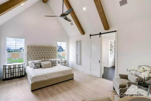 bedroom with ceiling fan, light hardwood / wood-style floors, multiple windows, and a barn door