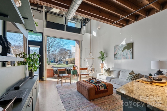 living room with a towering ceiling and concrete floors